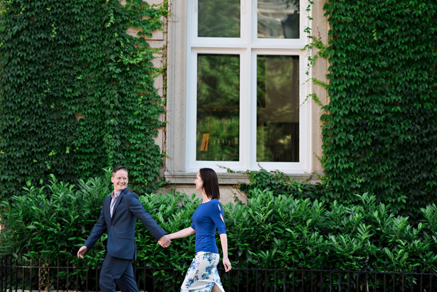 A cute couple walk the philadelphia streets with an ivy wall behind them.